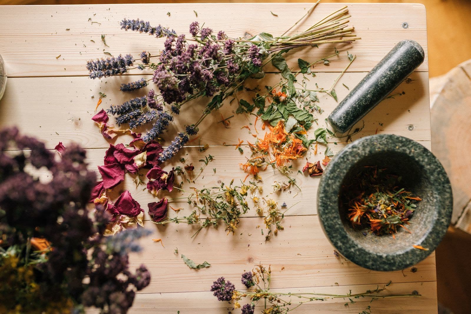 Dried botanicals and a stone mortar laid out on the workbench